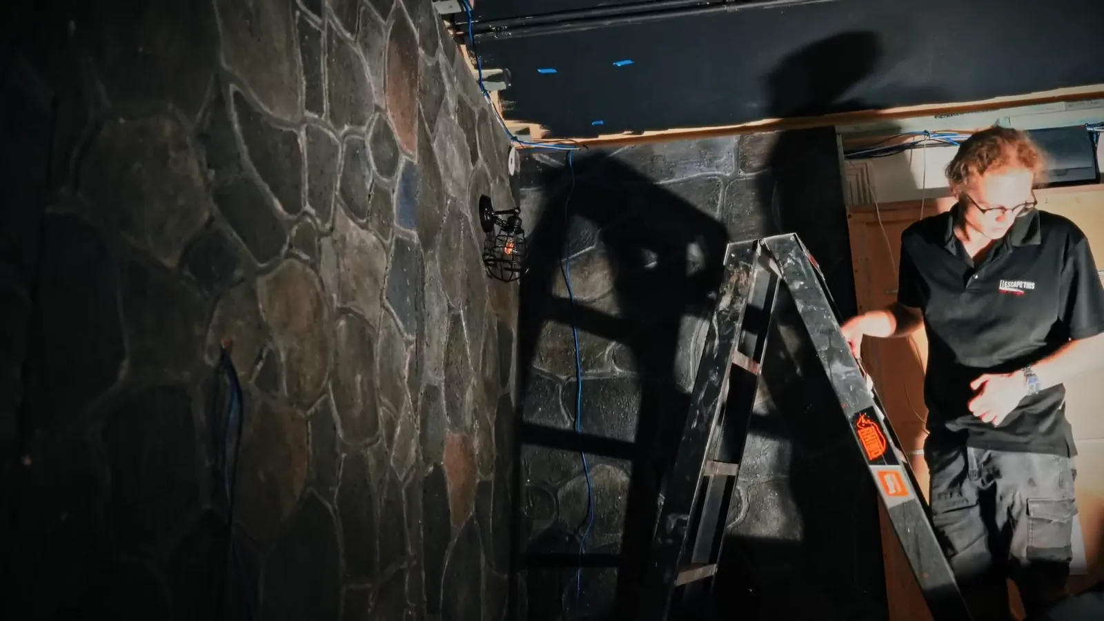 A crew member installing a stone-wall set in a new Escape This escape room